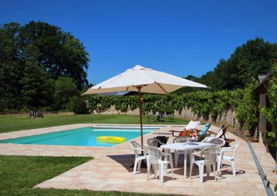 Vue sur la piscine de l'Orangerie entourée de son vaste jardin arboré